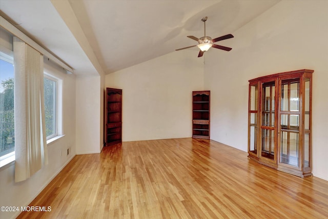 empty room featuring vaulted ceiling with skylight, light hardwood / wood-style flooring, and ceiling fan