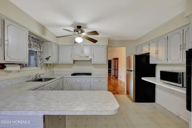 kitchen featuring appliances with stainless steel finishes, sink, kitchen peninsula, ceiling fan, and light hardwood / wood-style floors