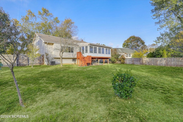 back of property with a yard, a deck, and central AC