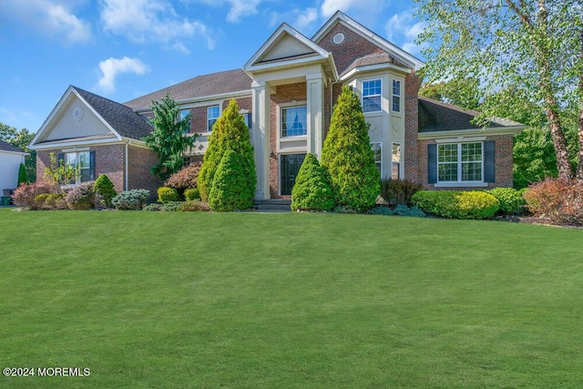 greek revival house with a front lawn and brick siding