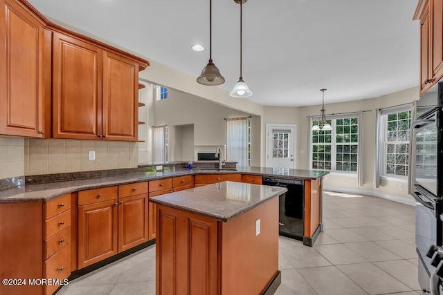 kitchen featuring brown cabinets, a peninsula, a sink, black appliances, and backsplash