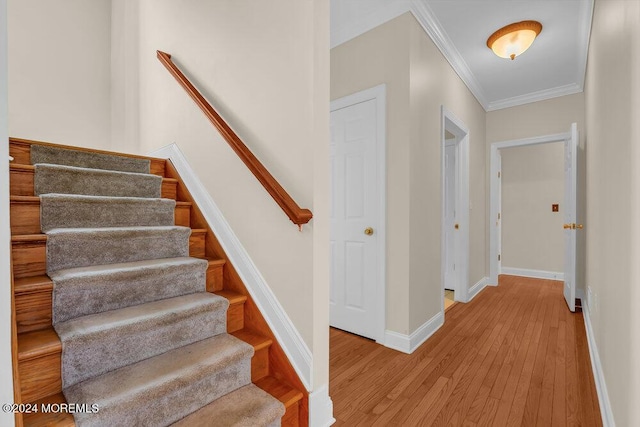 stairs with baseboards, wood finished floors, and ornamental molding