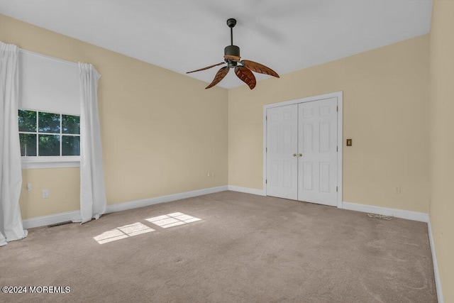 unfurnished bedroom with ceiling fan, a closet, carpet, and baseboards