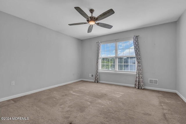 carpeted empty room featuring baseboards, visible vents, and a ceiling fan