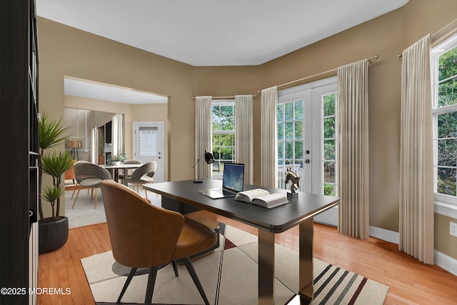 home office with french doors, baseboards, and light wood finished floors