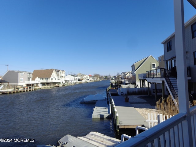 dock area with a water view, a residential view, and stairs