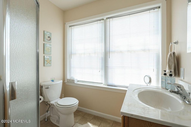 bathroom with baseboards, vanity, tile patterned floors, toilet, and a wealth of natural light