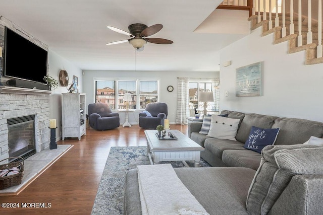 living area with dark wood-style flooring, ceiling fan, stairs, and a fireplace