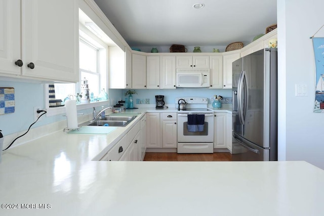 kitchen featuring wood finished floors, white appliances, light countertops, white cabinetry, and a sink