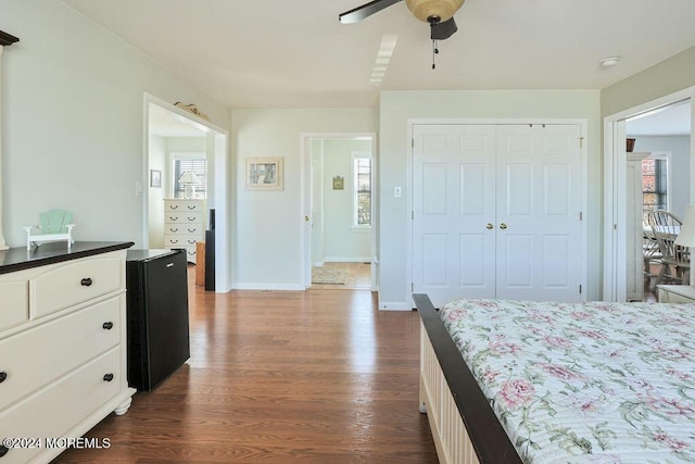 bedroom with baseboards, ceiling fan, a closet, and dark wood-style flooring