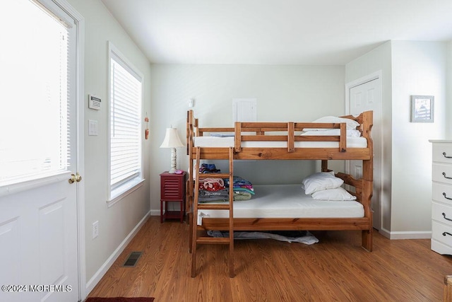 bedroom featuring baseboards, multiple windows, wood finished floors, and visible vents