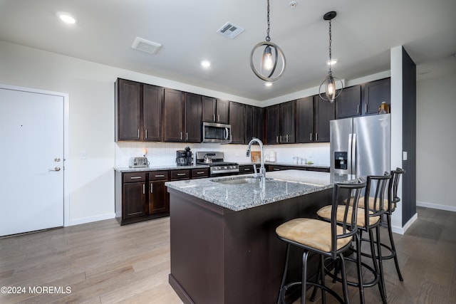 kitchen with light stone countertops, a kitchen bar, light hardwood / wood-style flooring, sink, and stainless steel appliances