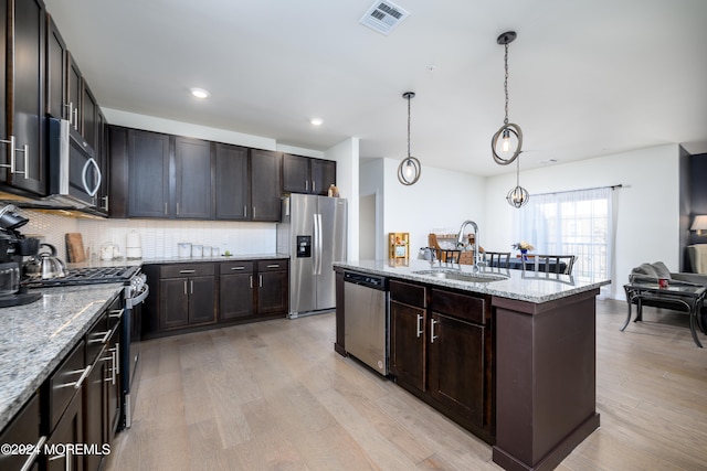 kitchen featuring sink, stainless steel appliances, decorative light fixtures, light hardwood / wood-style flooring, and a kitchen island with sink