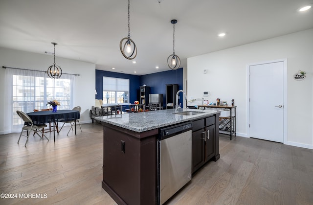 kitchen with light wood-type flooring, sink, stainless steel dishwasher, and a kitchen island with sink