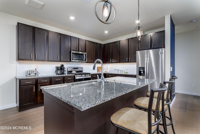 kitchen featuring appliances with stainless steel finishes, tasteful backsplash, sink, and light hardwood / wood-style floors