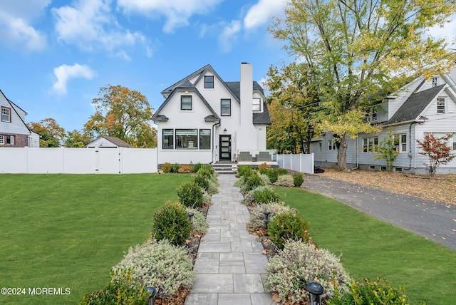 back of house with a chimney, fence, a lawn, and stucco siding