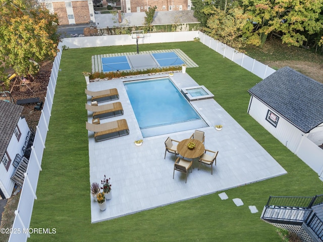 view of pool featuring a pool with connected hot tub, a fenced backyard, an outdoor structure, and a lawn