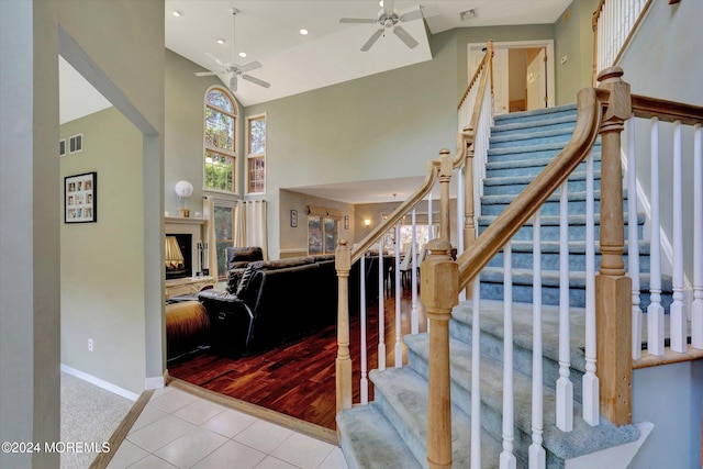 staircase with hardwood / wood-style floors, high vaulted ceiling, and ceiling fan