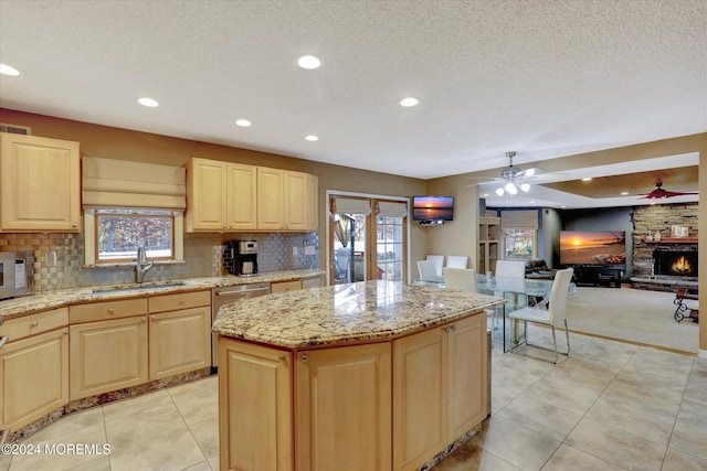 kitchen featuring a fireplace, plenty of natural light, a kitchen island, and sink