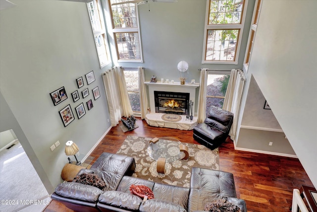 living room featuring a high ceiling, hardwood / wood-style flooring, ceiling fan, and a healthy amount of sunlight