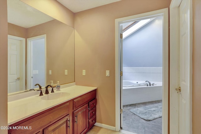 bathroom with tiled tub, tile patterned flooring, vanity, and a skylight