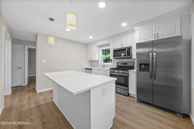 kitchen with light wood-type flooring, white cabinets, hanging light fixtures, and stainless steel appliances