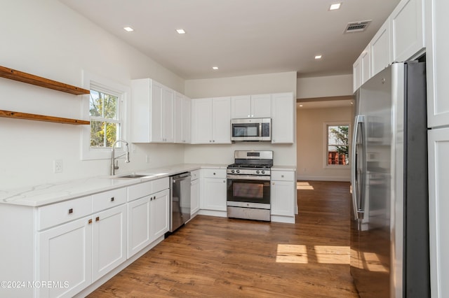 kitchen with light stone counters, white cabinetry, appliances with stainless steel finishes, dark hardwood / wood-style floors, and sink