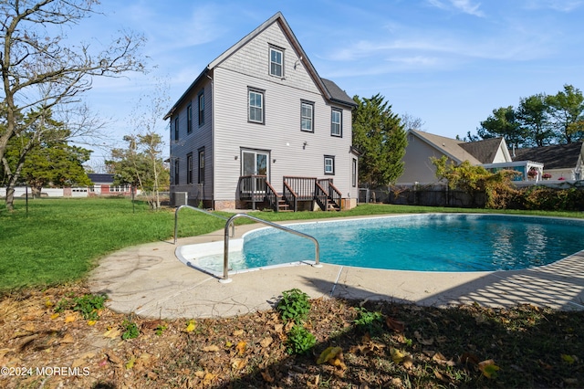 rear view of property with central AC, a lawn, and a pool side deck