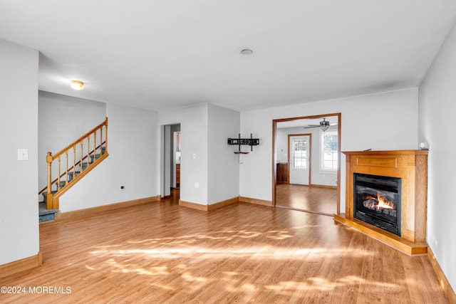 314 Ashford Rd, Toms River, NJ 08755 - unfurnished living room with light wood-style flooring, stairway, a glass covered fireplace, and a ceiling fan