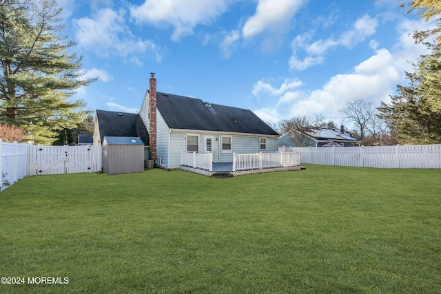 rear view of property with a deck, a storage unit, and a lawn