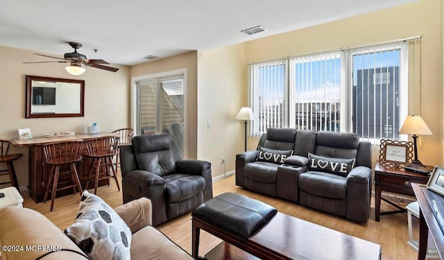 living room with ceiling fan, light hardwood / wood-style flooring, bar, and plenty of natural light