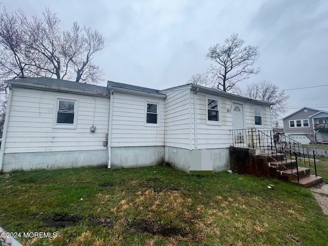 rear view of property featuring a garage and a yard