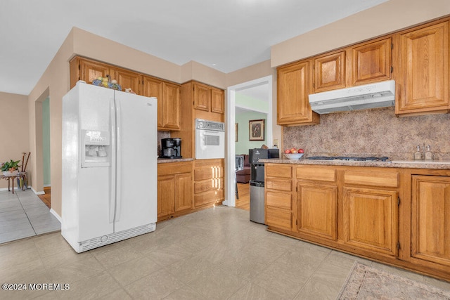 kitchen with backsplash, white appliances, and light tile patterned floors