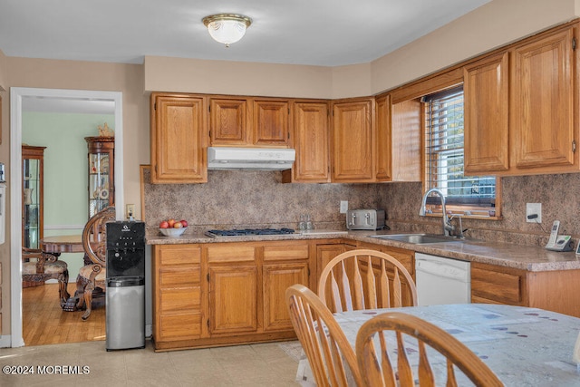 kitchen with tasteful backsplash, sink, stainless steel gas cooktop, white dishwasher, and light stone counters