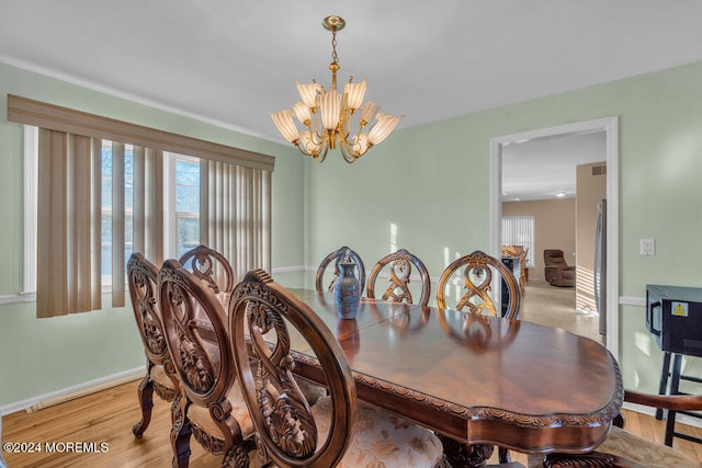 dining area with light hardwood / wood-style floors and a chandelier