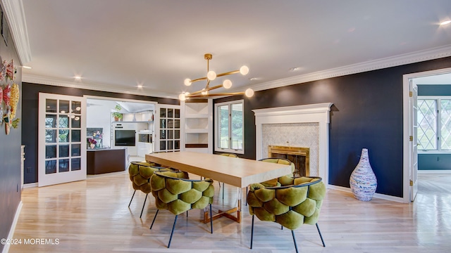 dining space with french doors, light wood-type flooring, an inviting chandelier, and ornamental molding