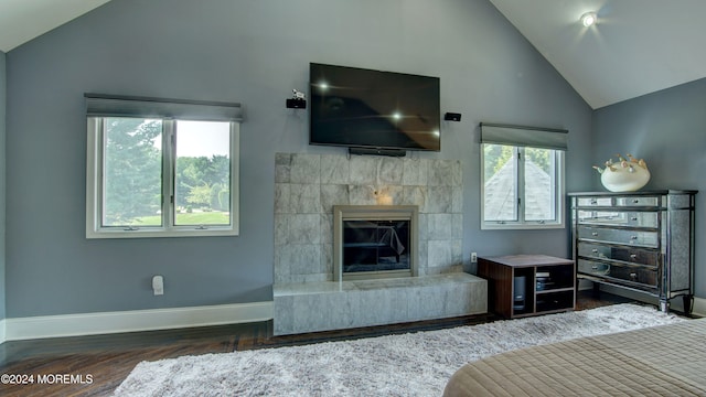 unfurnished bedroom featuring high vaulted ceiling, dark hardwood / wood-style floors, and a tile fireplace