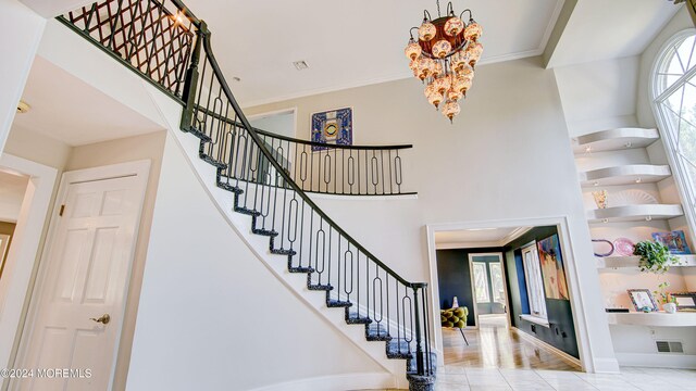 staircase with a chandelier, hardwood / wood-style flooring, and crown molding