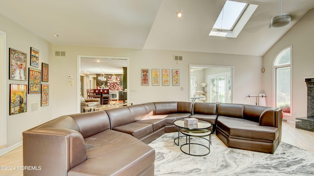 living room with lofted ceiling with skylight and light wood-type flooring