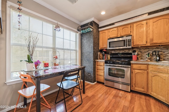 kitchen featuring a wealth of natural light, appliances with stainless steel finishes, crown molding, and light hardwood / wood-style flooring