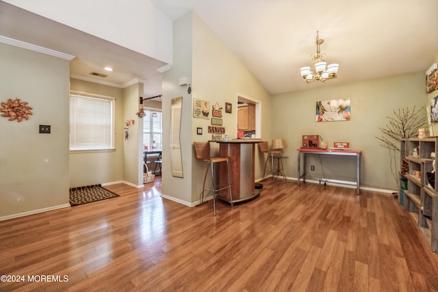 interior space featuring lofted ceiling, wood-type flooring, a notable chandelier, and ornamental molding