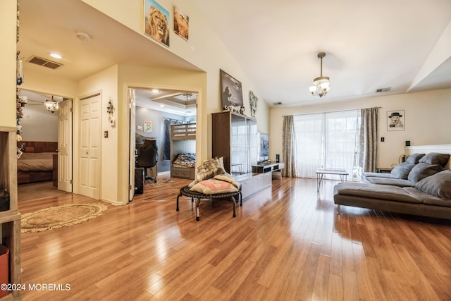 living room with light hardwood / wood-style flooring, a notable chandelier, and lofted ceiling