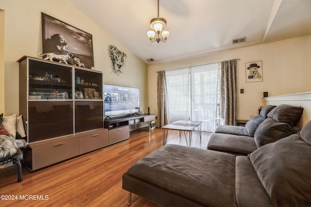 living room featuring vaulted ceiling, hardwood / wood-style flooring, and a notable chandelier