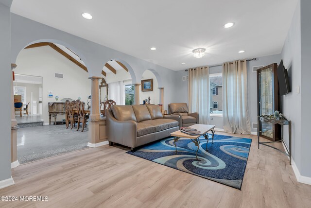 living room featuring ornate columns, light hardwood / wood-style flooring, and vaulted ceiling