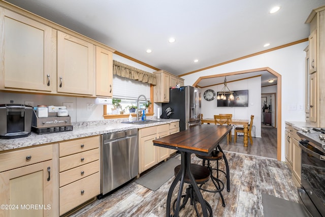 kitchen featuring a sink, appliances with stainless steel finishes, ornamental molding, light brown cabinetry, and wood finished floors