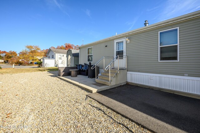 rear view of property with a storage unit, a patio, and an outbuilding