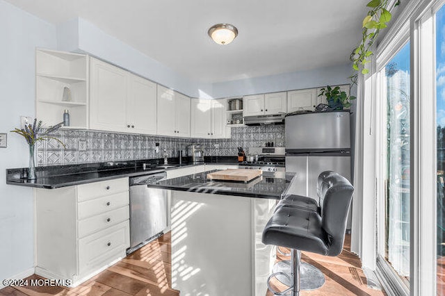 kitchen featuring stainless steel appliances, a breakfast bar, backsplash, a center island, and white cabinets