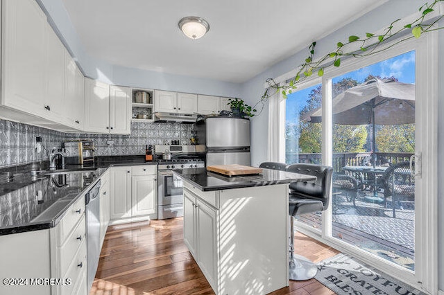 kitchen featuring white cabinetry, appliances with stainless steel finishes, tasteful backsplash, a center island, and dark wood-type flooring