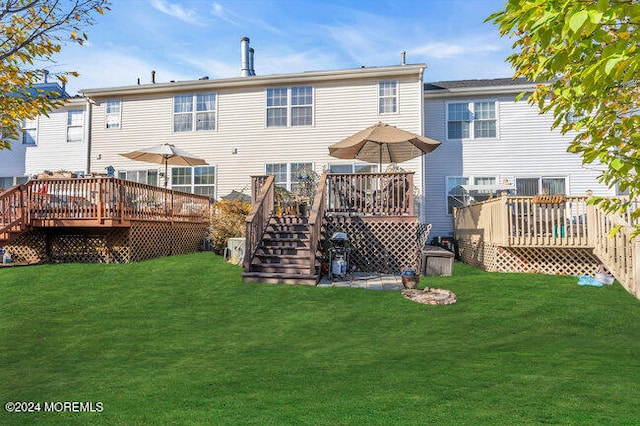 rear view of house featuring a wooden deck and a yard