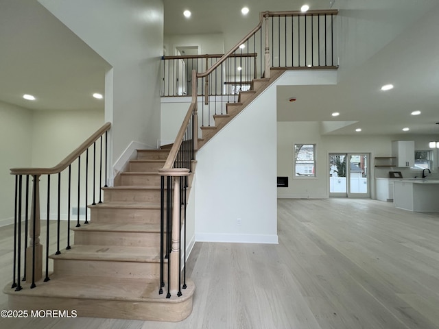 stairway featuring sink, hardwood / wood-style floors, and a towering ceiling